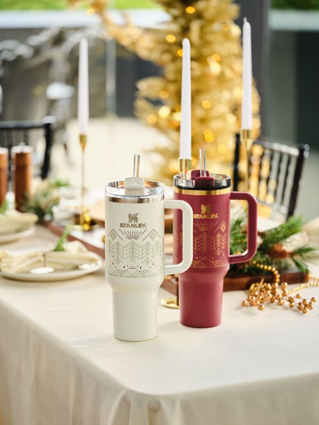 Two of Stanley's Quencher tumblers in white and red featuring an etched design.